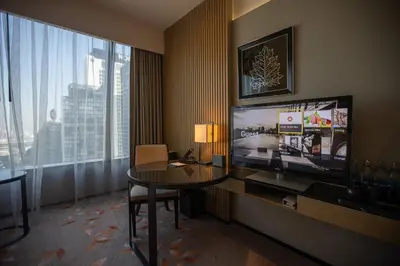 a hotel room with a table and a large television at The Okura Prestige Bangkok in Bangkok