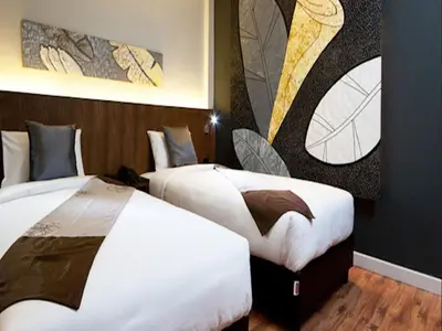 two beds in a hotel room with paintings on the wall at Siam Swana in Bangkok