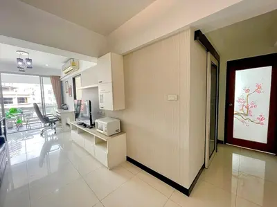 a room with a kitchen with a counter and a television at Baan Sabai Rama IV Apartment in Bangkok