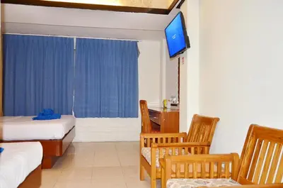a room with two beds and a desk and a television at At Bangkok Hotel in Bangkok