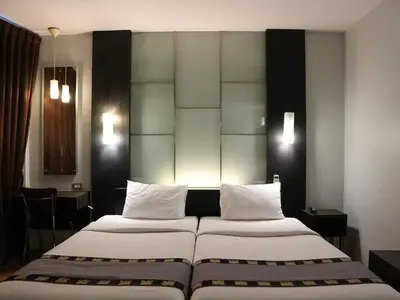 two beds with white pillows in a hotel room at Swana Bangkok Hotel in Bangkok