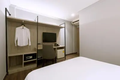 a bedroom with a bed and a desk and a television at Maxim's Inn in Bangkok