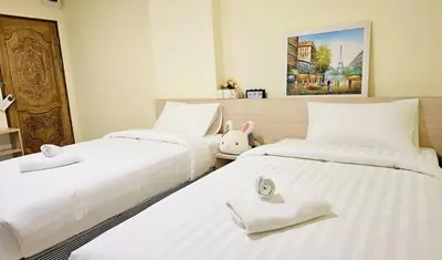 two beds with white sheets and a stuffed rabbit sitting between them at Be My Guest 36 in Bangkok
