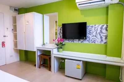 a room with a desk with a tv on a green wall at The Konnect Hotel in Bangkok