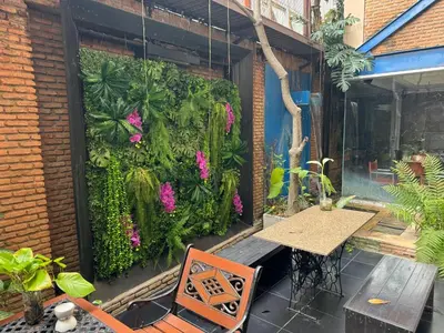 a patio with a table and a green wall with flowers at Silom Convent Garden in Bangkok