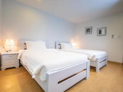 a white bedroom with two beds and a night stand at The Kinn Bangkok in Bangkok