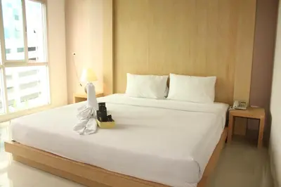 a bedroom with a large white bed with a lamp on it at Bansabai Sabaidee Service Apartment in Bangkok