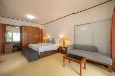 a bedroom with a bed and a couch and a table at Bangkok Rama Hotel in Bangkok