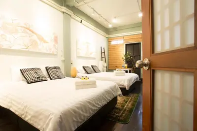 a room with two beds and a door with a door at The Orientale Hostel in Bangkok