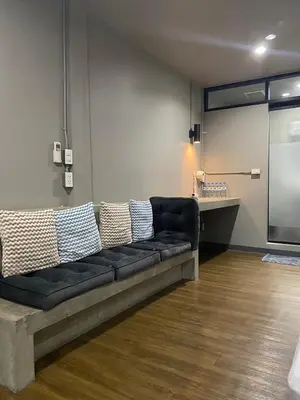a black couch in a room with a kitchen at Yaksa Private in Bangkok