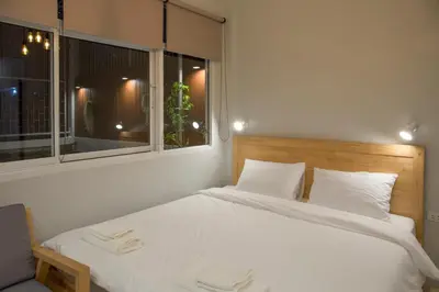 a bedroom with a white bed and two windows at Ekanake hostel in Bangkok