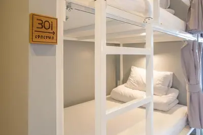 a bunk bed with white bunk beds in a room at Ekanake hostel in Bangkok