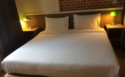 a large white bed in a room with two lamps at Bourbon St. Boutique Hotel in Bangkok