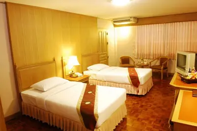 a hotel room with two beds and a television at Silom Village Inn in Bangkok