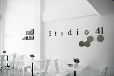 a dining room with white tables and white chairs at Studio 41 Salaya-Sai4 in Nakhon Pathom