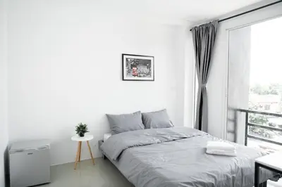 a white bedroom with a bed and a window at Studio 41 Salaya-Sai4 in Nakhon Pathom
