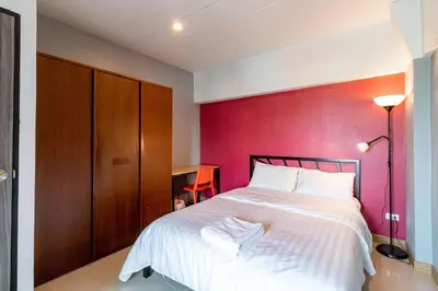 a bedroom with a bed with a red wall at Living Naraa Place in Bangkok