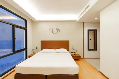 a bedroom with a large bed and a large window at Marvin Suites Hotel in Bangkok