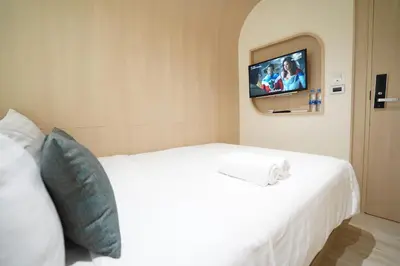 a bedroom with a white bed with a tv on the wall at W 21 Hotel Bangkok in Bangkok