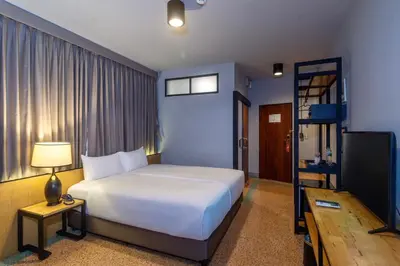 a bedroom with a large white bed and a television at W22 by Burasari in Bangkok