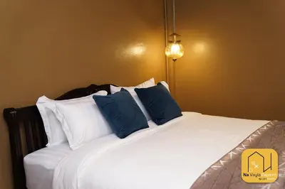 a large white bed with blue pillows in a room at Na Vayla PaPlern in Bangkok
