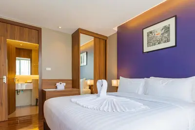 a bedroom with a large white bed with purple walls at Amp Am House Bangkok Hotel in Bangkok
