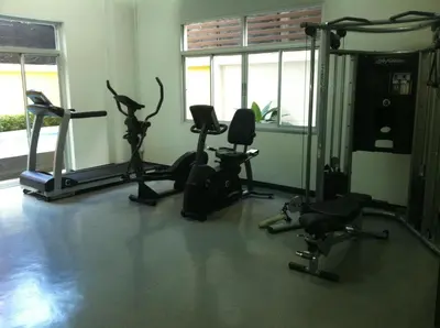 a gym with treadmills and exercise bikes and windows at T Series Place Serviced Apartment in Bangkok