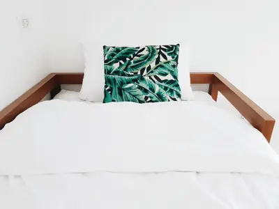 a white bed with a green pillow on it at LITA Bangkok in Bangkok