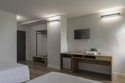 a bedroom with a bed and a desk with a television at Carnation Residence in Samut Prakan