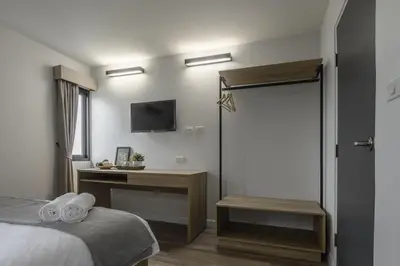 a bedroom with a bed and a desk and a television at Carnation Residence in Samut Prakan
