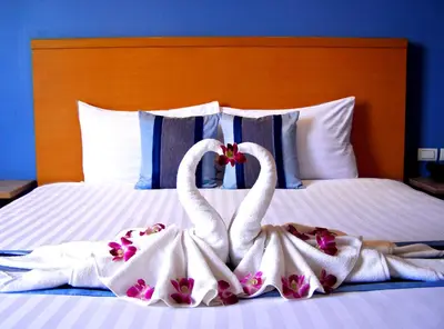 two swans dressed in towels sitting on a bed at Iyarin @ Tuk Chang Hotel in Bangkok