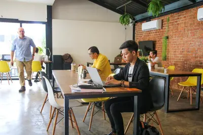 a group of men sitting at a table with a laptop at the CAPSULE by UnionSPACE in Bangkok