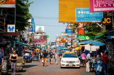 a busy city street with people walking and a car on the street at Suneta Hostel Khaosan in Bangkok