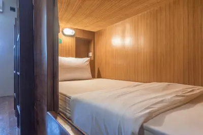 a small room with a bed and wooden walls at Suneta Hostel Khaosan in Bangkok