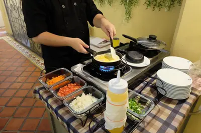 a person cooking food in a pot on a stove at Siri Heritage Bangkok Hotel in Bangkok