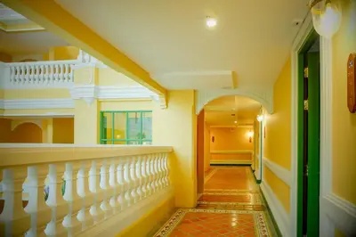 a hallway with yellow walls and white stairs at Siri Heritage Bangkok Hotel in Bangkok
