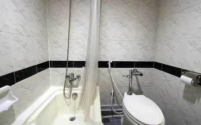 a bathroom with a toilet and a bath tub at Grand Tower Inn Rama 6 in Bangkok