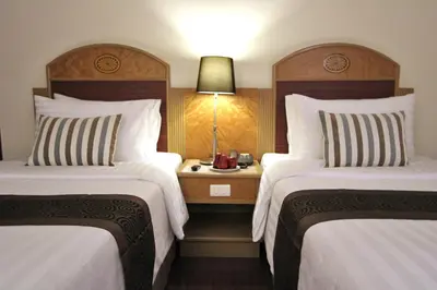 a hotel room with two beds and a table with a lamp at Grand Tower Inn Rama 6 in Bangkok