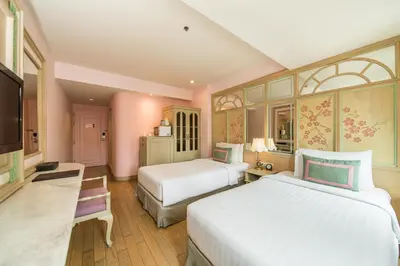 a hotel room with two beds and a television at La Petite Salil Sukhumvit 11 in Bangkok