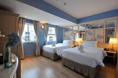 two beds in a hotel room with blue walls at La Petite Salil Sukhumvit 11 in Bangkok