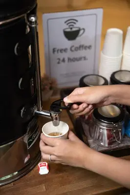 a person is putting a cup of coffee in a coffee machine at Nantra Sukhumvit 39 in Bangkok