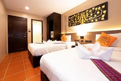 a hotel room with two beds and a door at Baan Sukhumvit Soi 20 in Bangkok