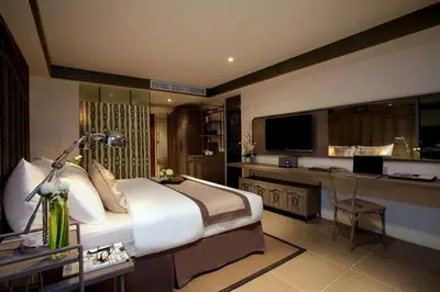 a bedroom with a large bed and a desk and a kitchen at Riva Surya Bangkok in Bangkok
