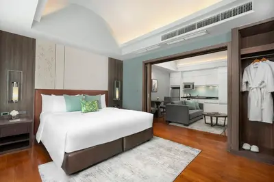 a bedroom with a large bed and a living room at Hotel Mermaid Bangkok in Bangkok