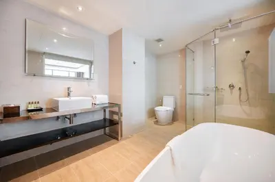 a white bathroom with a sink and a shower at Hotel Mermaid Bangkok in Bangkok