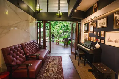 a waiting room with a couch and a piano at Narra House Sukhumvit58 in Bangkok