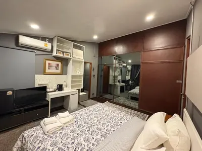 a bedroom with a bed and a desk and a television at Narra House Sukhumvit58 in Bangkok