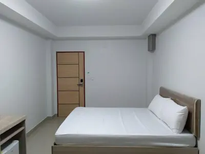 a bedroom with a white bed and a wooden door at Roseate Bangkok Hotel in Bangkok