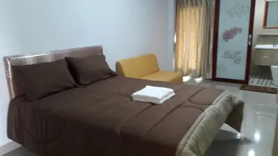 a bedroom with a large bed with a yellow chair at Roseate Bangkok Hotel in Bangkok