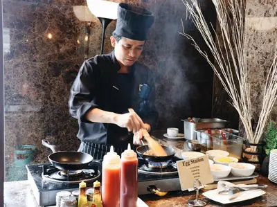a chef cooking food in a wok on a stove at Zayn Hotel Bangkok - Airport Link Access in Bangkok